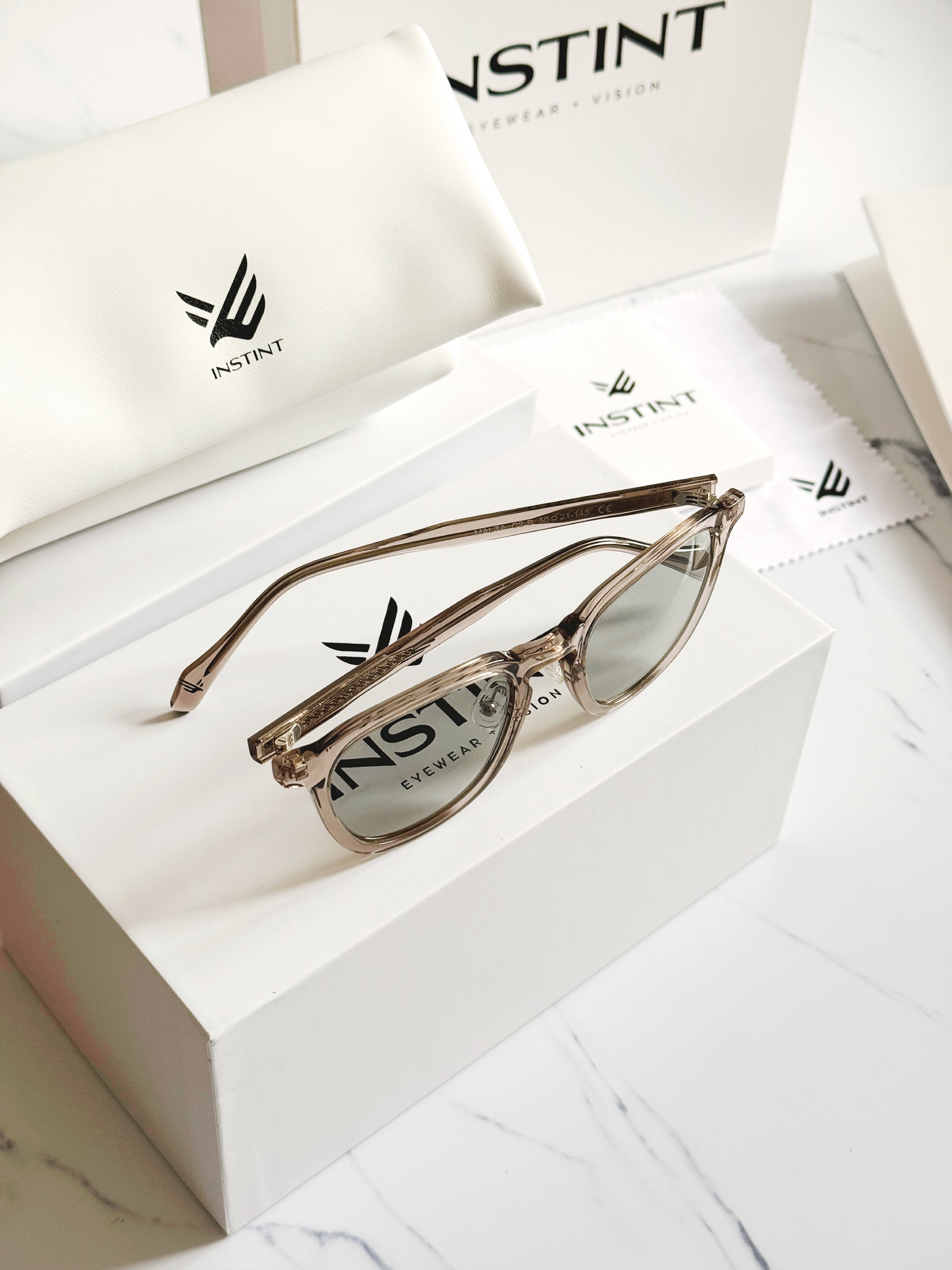 Confezione premium Instint Eyewear — astuccio rigido e panno in microfibra
