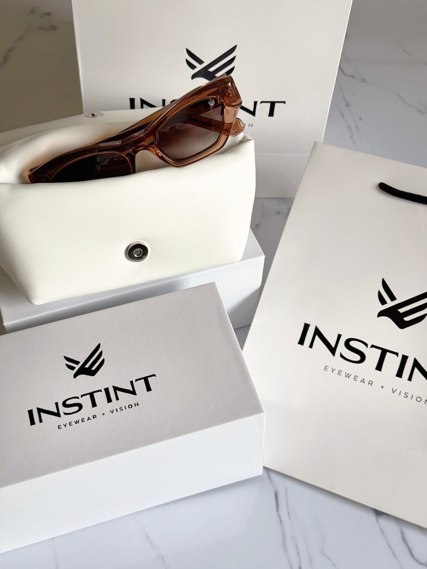 Confezione premium Instint Eyewear — astuccio rigido e panno in microfibra inclusi
